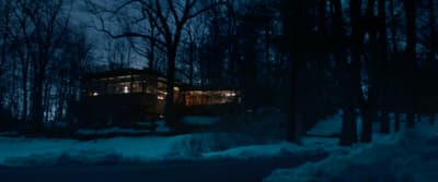 a cabin in the woods at night with snow on the ground