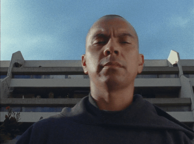 a man with his eyes closed standing in front of a building