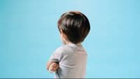 a little boy standing in front of a blue background