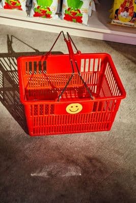 a red shopping basket with a smiley face on it