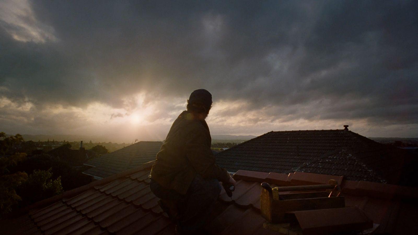 a man standing on top of a roof under a cloudy sky