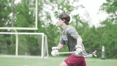 a young man holding a lacrosse racquet on top of a field