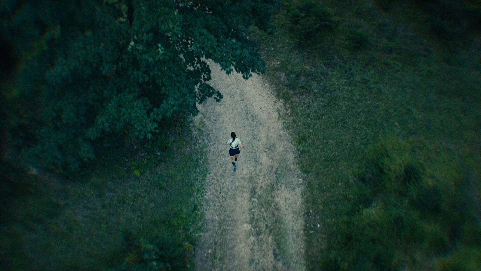 a person walking down a dirt road next to a forest