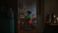 a woman sitting at a computer desk in a dark room