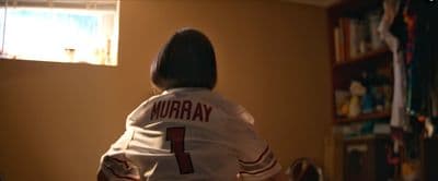 a woman in a baseball uniform standing in a living room