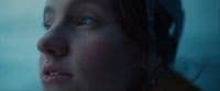 a close up of a woman's face with the sky in the background