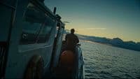a man standing on the back of a boat at sunset