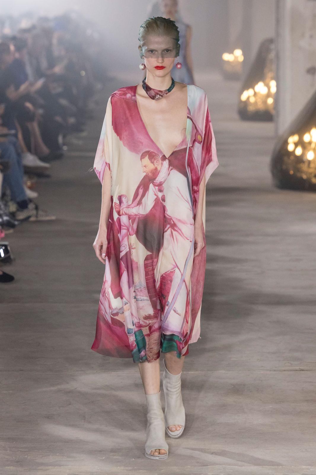 a woman walking down a runway in a dress