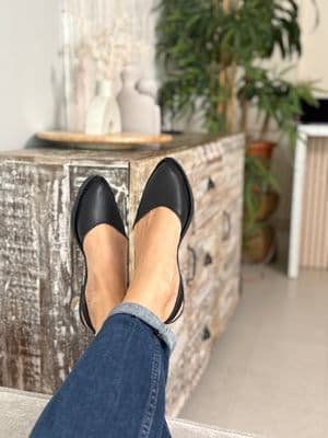 a woman's feet in black shoes sitting on a dresser