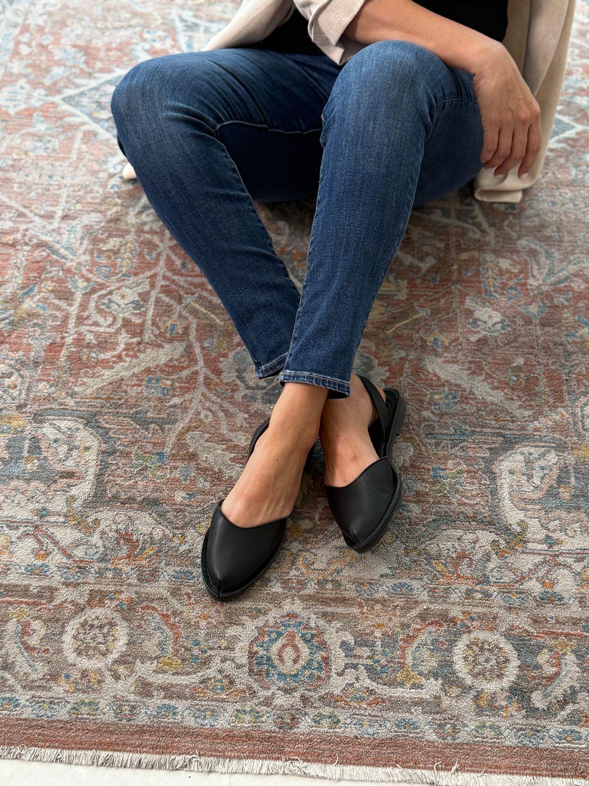 a woman sitting on a rug wearing black shoes