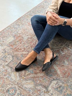 a woman sitting on the floor wearing black shoes