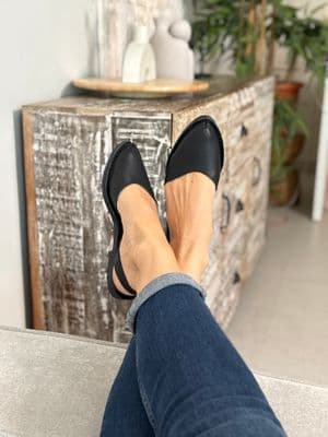 a woman's feet wearing black shoes and jeans