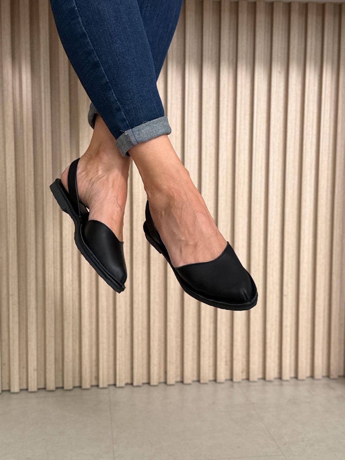 a woman sitting on a stool wearing black shoes