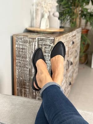a woman's feet in black shoes sitting on a bench