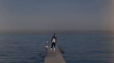 a man standing on a pier in the middle of the ocean