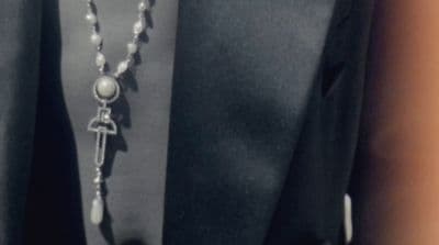a person wearing a black shirt and a necklace with a cross on it