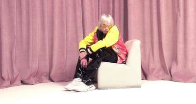 a person sitting on a chair in front of a curtain
