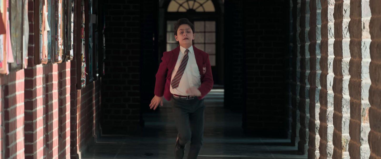 a man in a suit and tie walking through a hallway