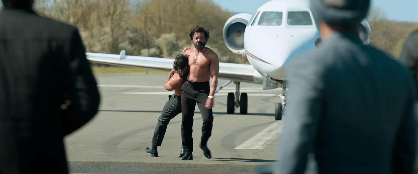 a shirtless man walking towards a small plane