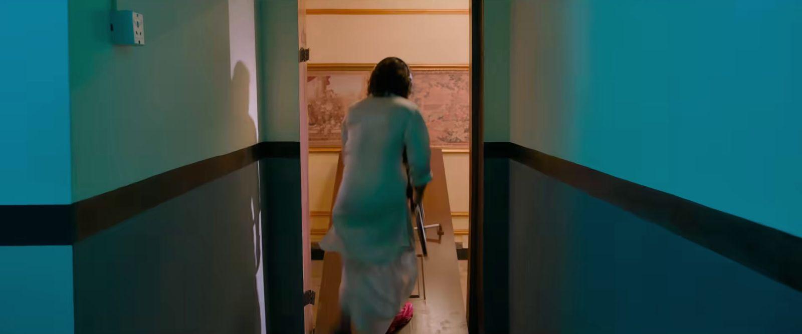 a woman walking down a hallway with a cane