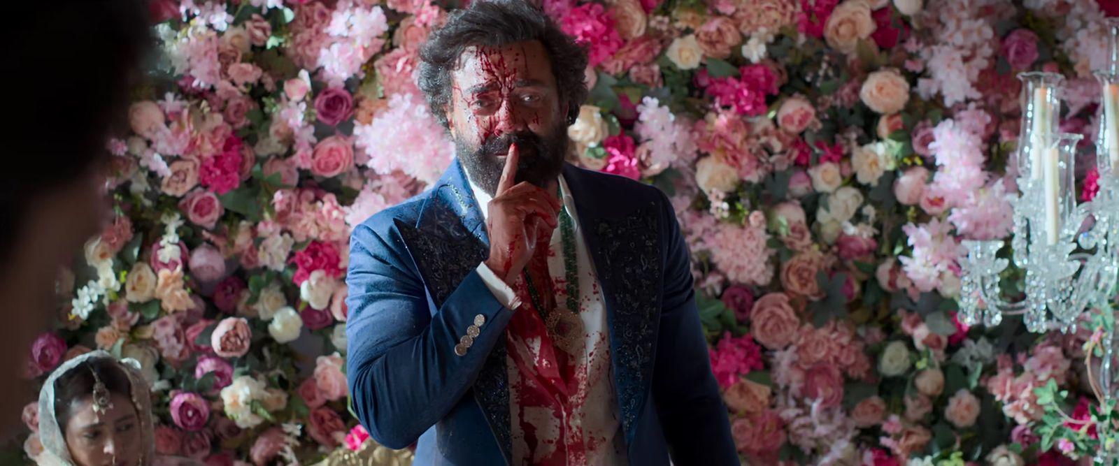a man in a suit and tie standing in front of a flower wall