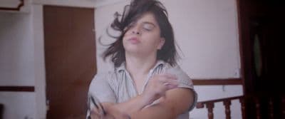 a woman standing in a room with her hair blowing in the wind