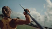 a woman holding a baseball bat on top of a field