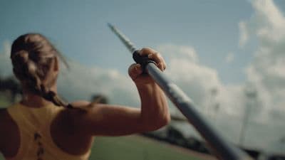 a woman holding a baseball bat on top of a field