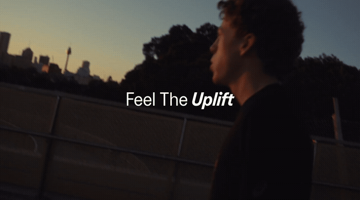 a young man standing in front of a fence with the words feel the uplift