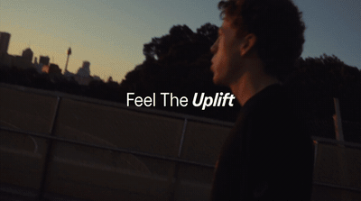 a young man standing in front of a fence with the words feel the uplift