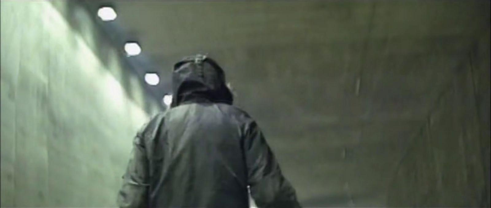 a man walking down a long hallway with lights on