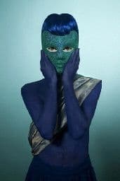 a woman in a blue bodysuit covering her face with her hands