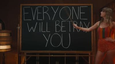 a woman standing in front of a blackboard with writing on it