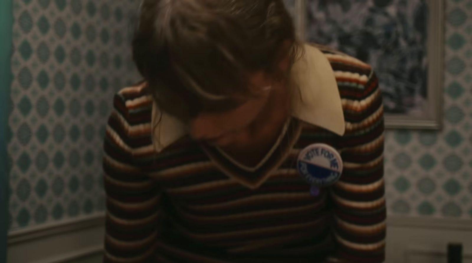 a woman standing in a room with a button on her neck