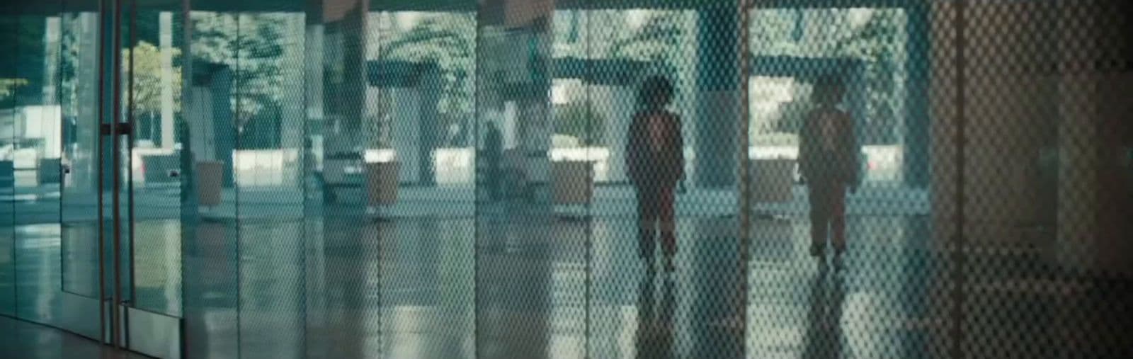 a couple of people standing in front of a glass wall