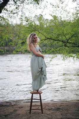 a woman standing on a stool by a river