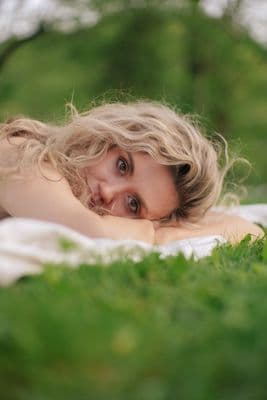 a woman laying on top of a lush green field