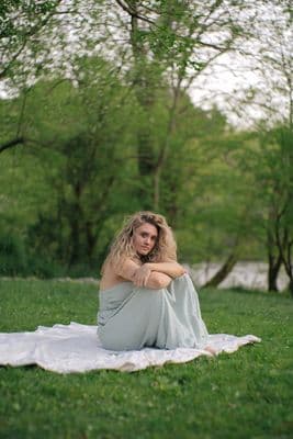 a woman sitting on a blanket in a park