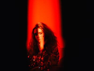 a woman with long hair standing in front of a red light