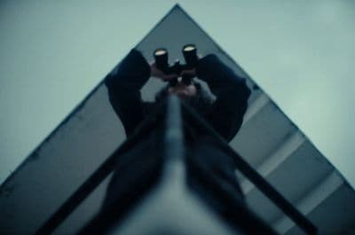 a man holding a pair of binoculars up to the sky