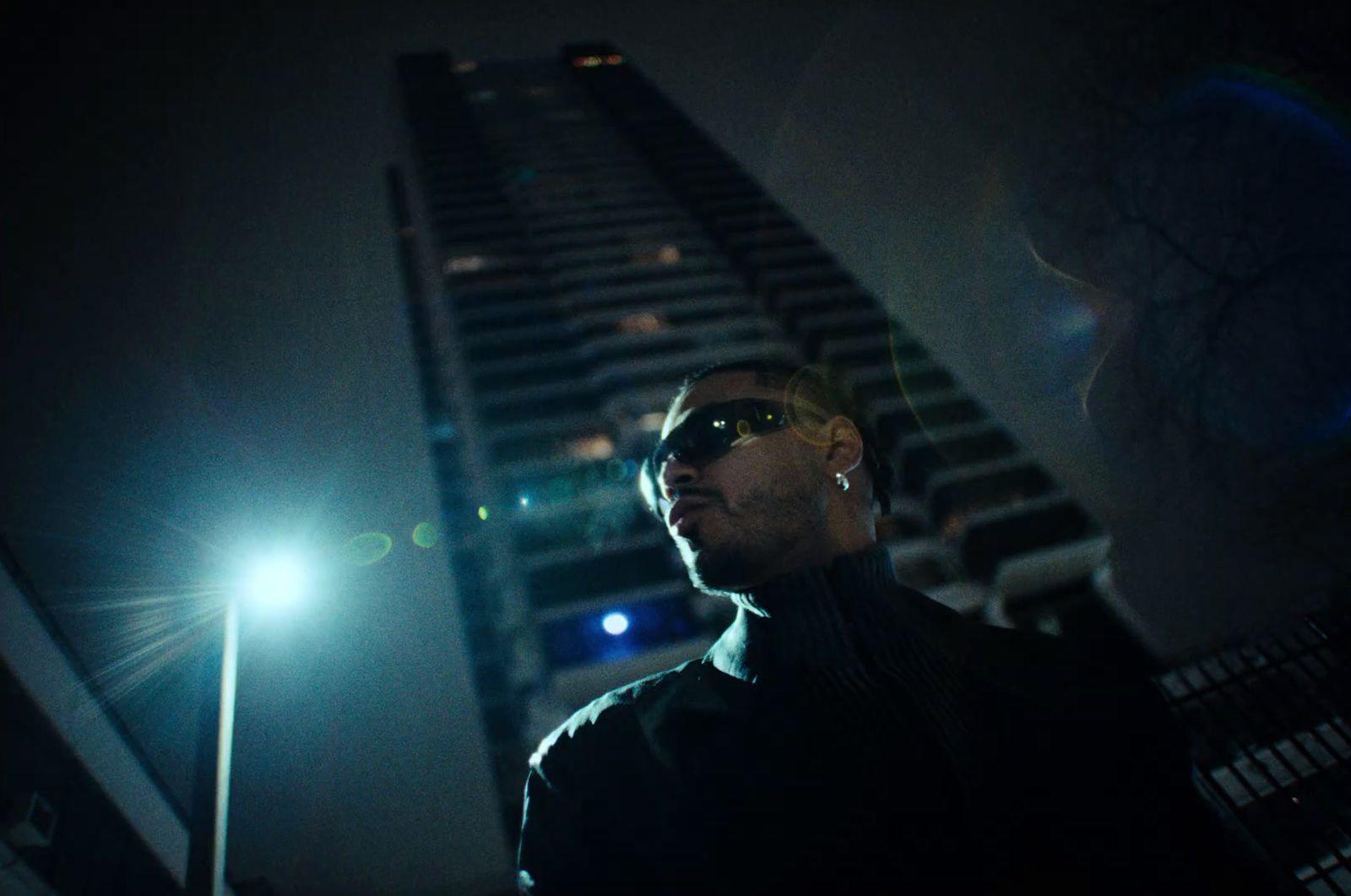 a man standing in front of a tall building at night