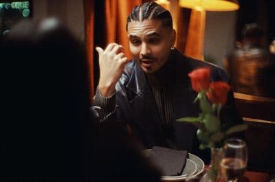 a man sitting at a table with a rose in front of him