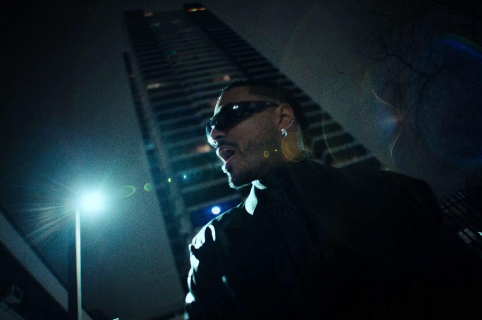 a man standing in front of a tall building at night
