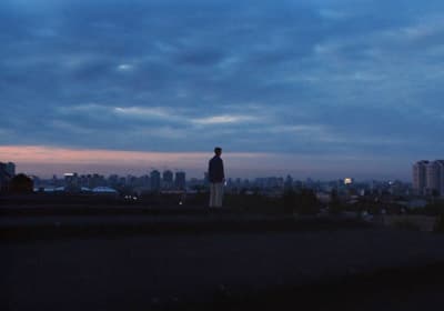 a man standing on top of a roof with a city in the background