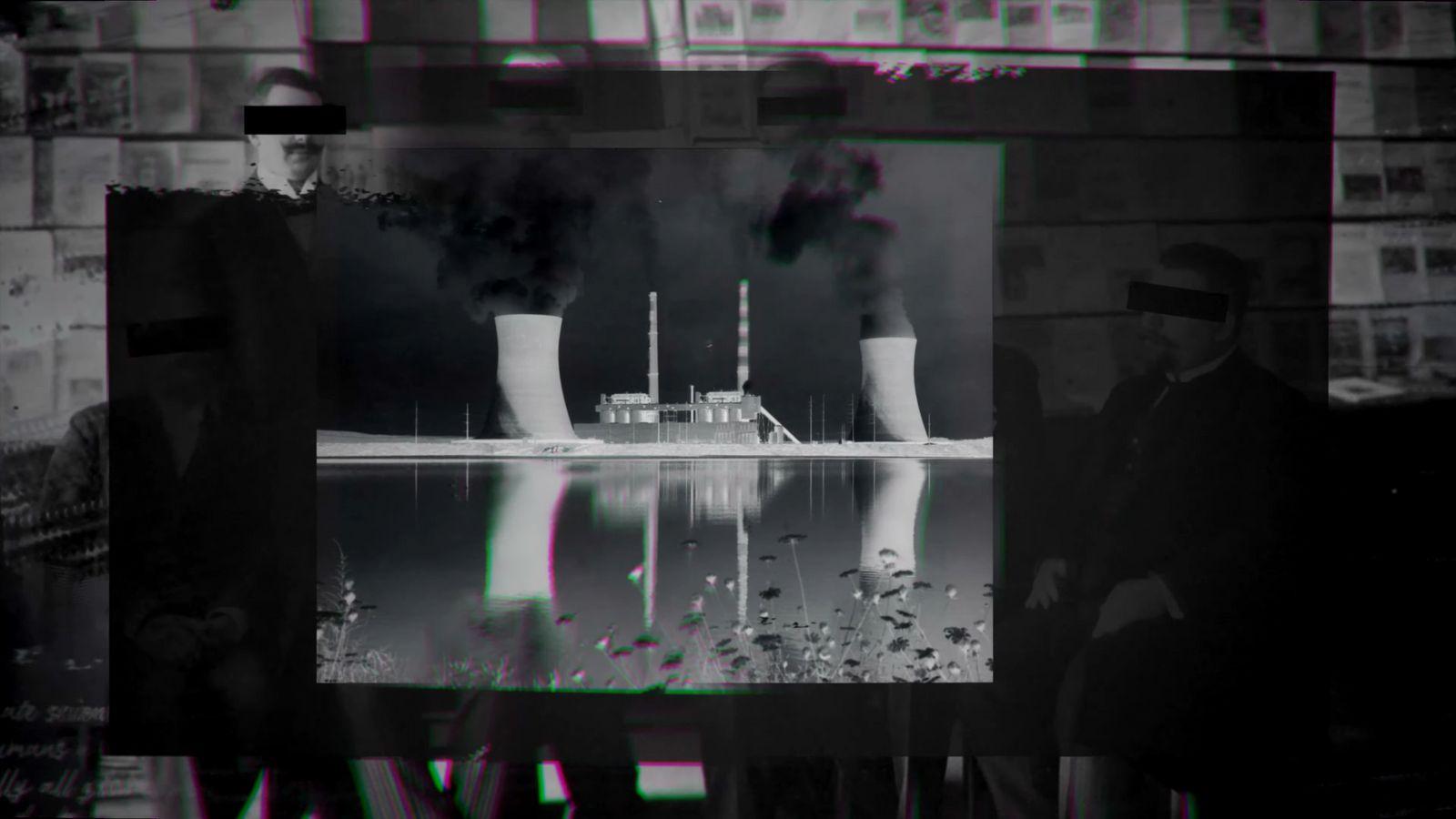 a black and white photo of a factory with smoke coming out of it