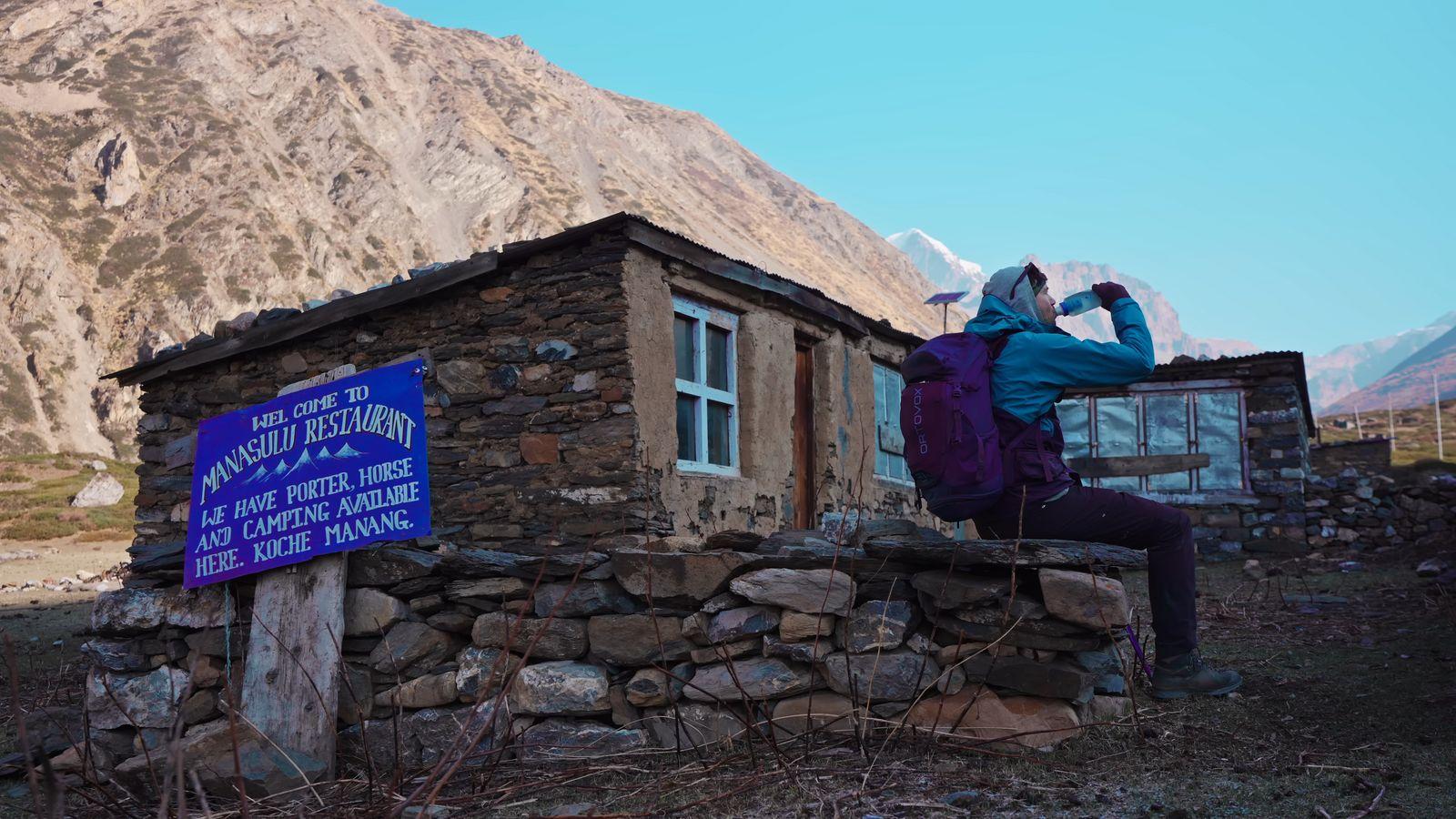 a woman standing on a rock wall next to a building