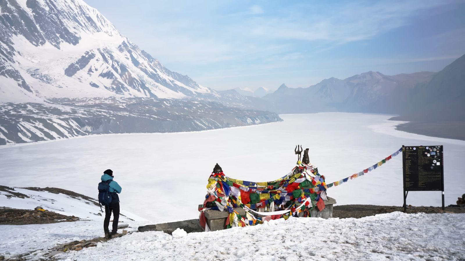 a person standing next to a mountain covered in snow