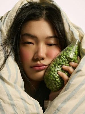 a woman wrapped in a blanket holding a green object