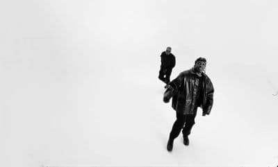 a black and white photo of two people walking