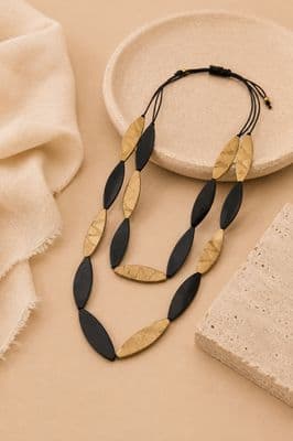 a black and gold necklace next to a white plate